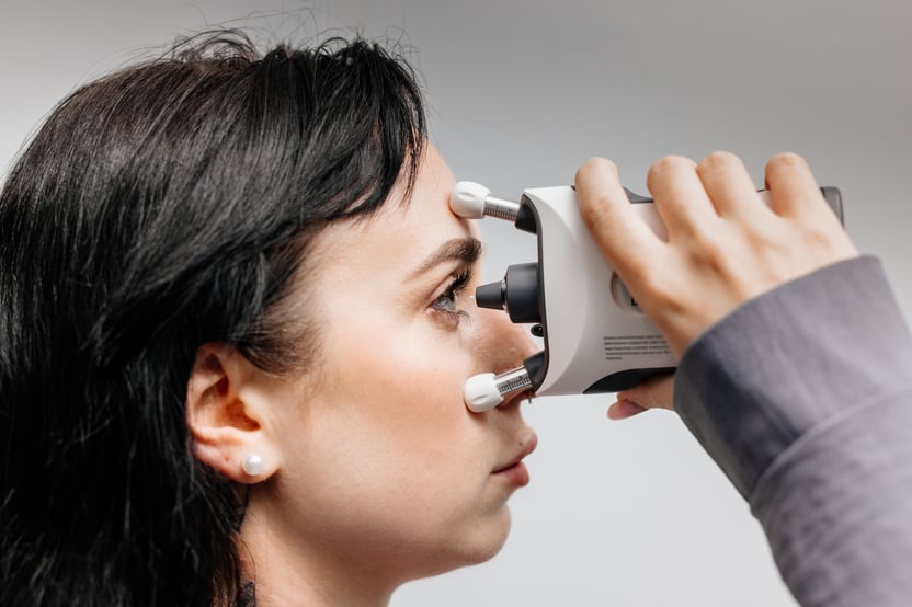 Close-up of a woman self-measuring her eye pressure with a handheld tonometer.