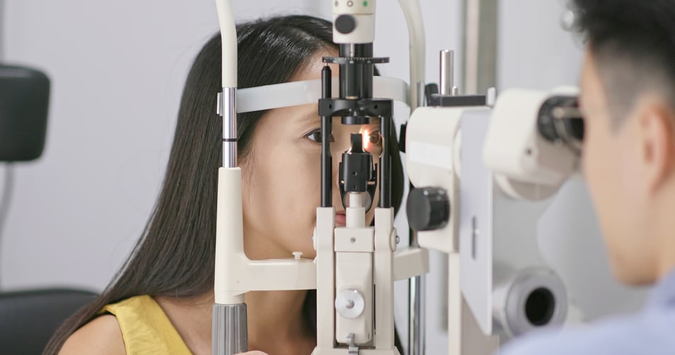 An eye doctor examining a female patient's eye using a slit lamp microscope