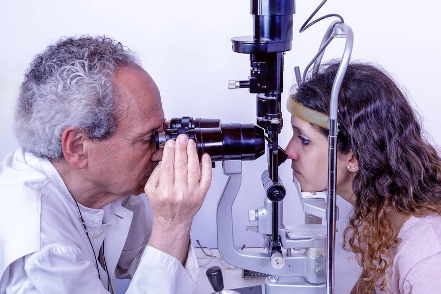 Ophthalmologist performing eye examination on female patient using slit lamp