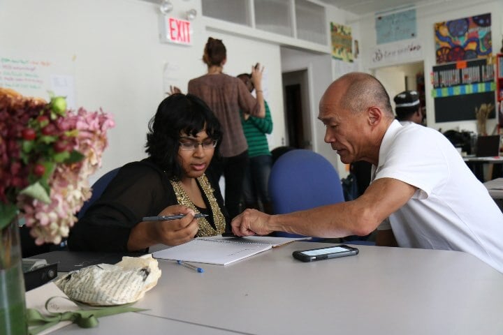 Man assisting woman with writing
