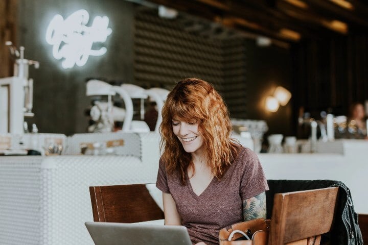 Woman working on computer in public restaurant